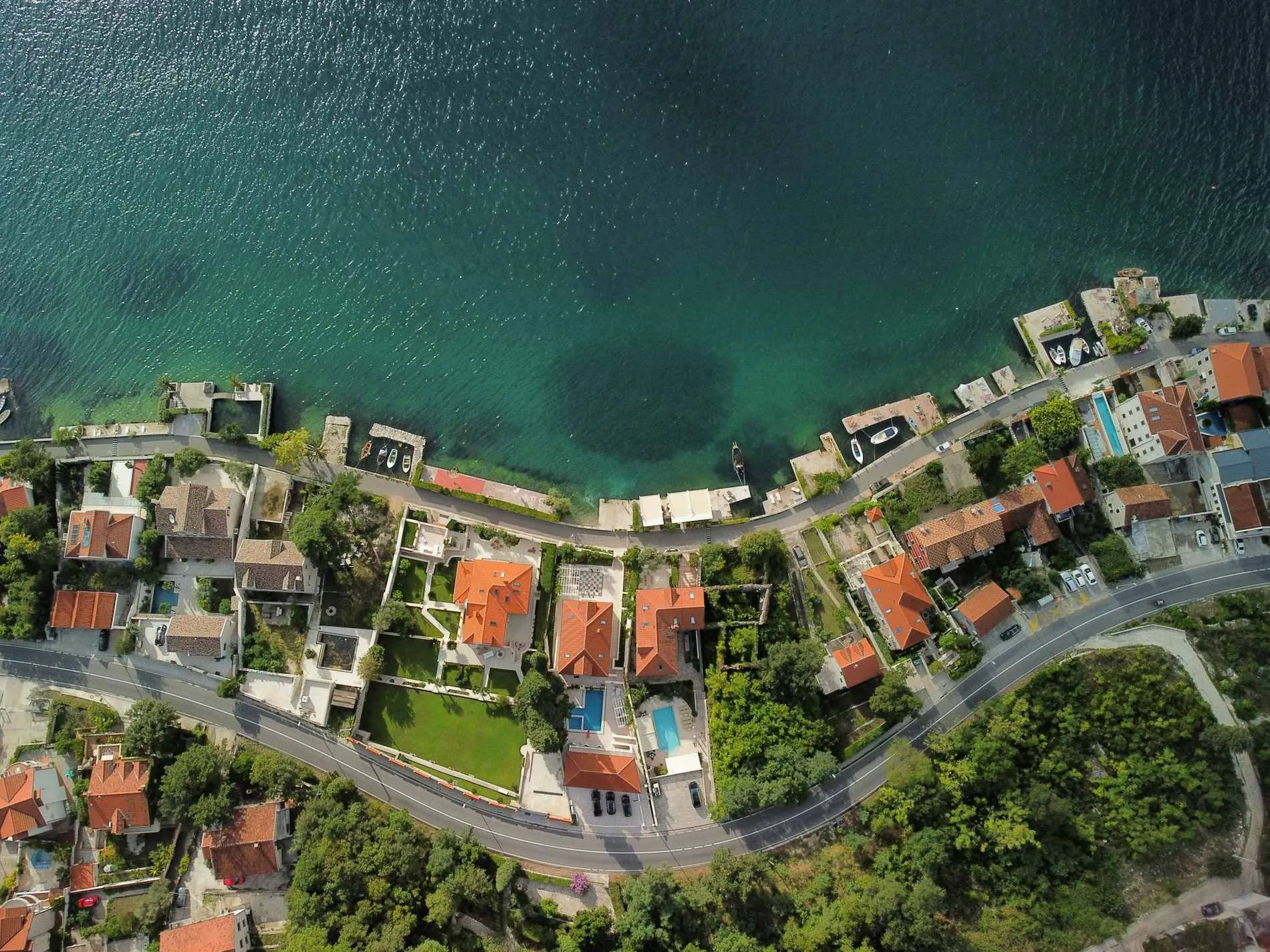Aerial view of a bay on the Montenegro coast, with a town, marina and hillside development visible from above